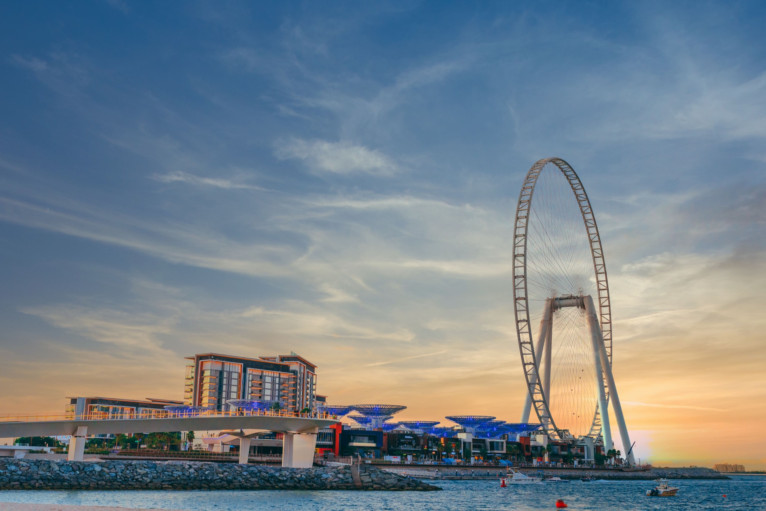 low-angle-shot-modern-design-building-with-huge-ferris-wheel-bluewaters-island-dubai-min